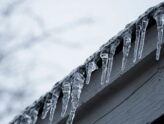 Low-shot of icicles hanging from a roof in winter.