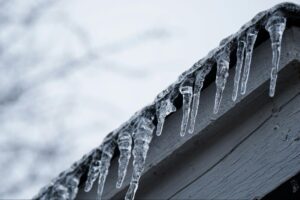 Low-shot of icicles hanging from a roof in winter.